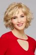 Woman in a chin length extra curly light gold blonde wig with side bangs