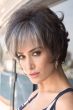 Woman in short grey curly wig with bangs
