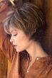 Woman in a long light brown pixie wig with fringe bangs and shorter, spiky layering in back