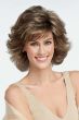 Woman in a medium brown, shoulder length blown out wig with dramatic layers and fringe bangs