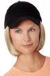 Woman in a solid black baseball cap with chin length light blonde hair attached
