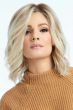 Woman in a shoulder length light blonde curly lace front wig with dark roots