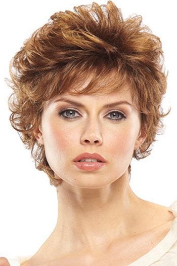 Woman in a long curly light auburn pixie wig with longer layers on top and side fringe bangs