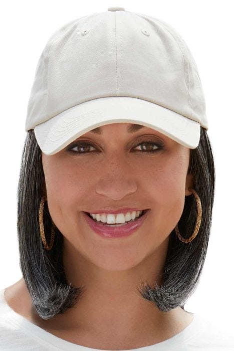 Woman in a solid beige baseball cap with shoulder length curled under light ash blonde hair attached