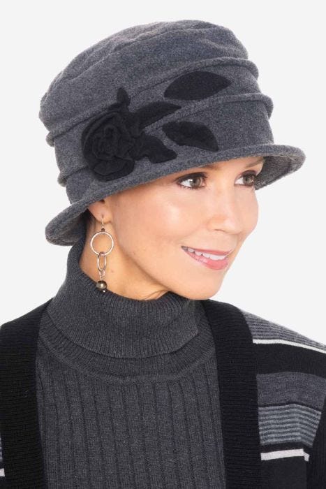 Woman in black cloche style winter fleece cancer hat with red accents and flower