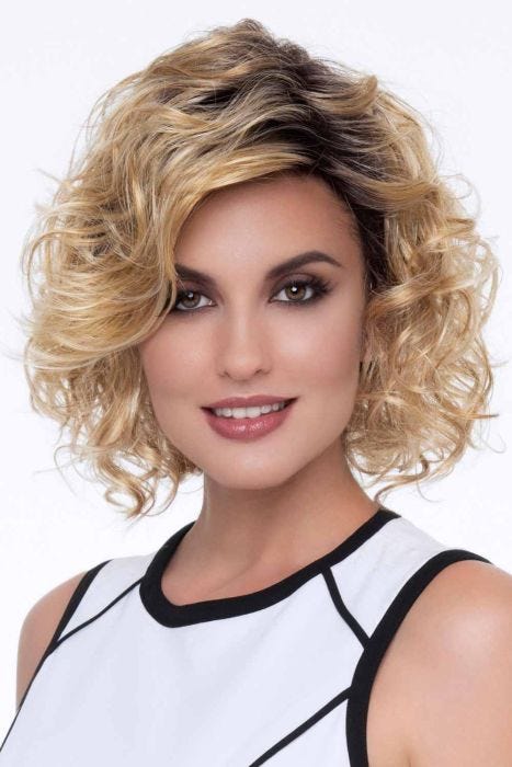 Woman in a shoulder length light blonde curly wig with long layers