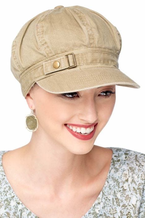 Woman in khaki chemo headwear featuring a newsboy style cap with side buckle