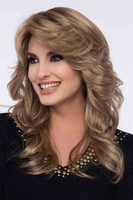 Woman in a past the shoulder curly light brown wig with feathered bangs