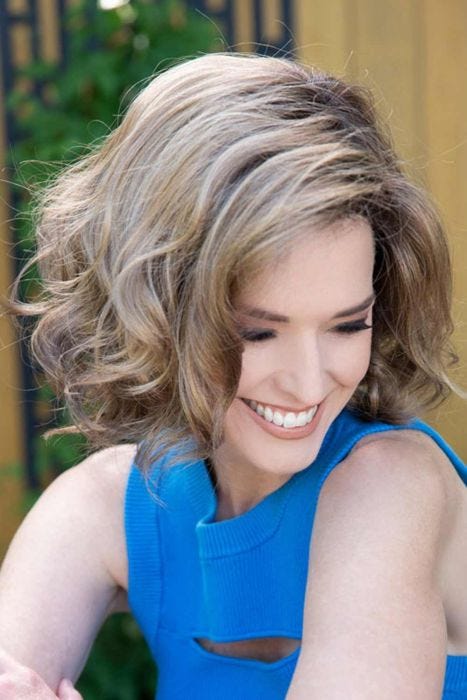 Woman in a chin length curly layered light blonde bob wig