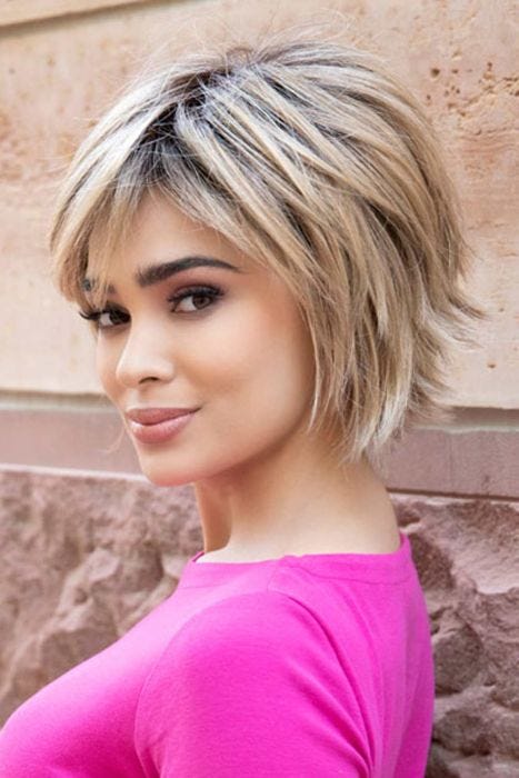 Woman in a shoulder length choppy light auburn bob wig with fringe bangs