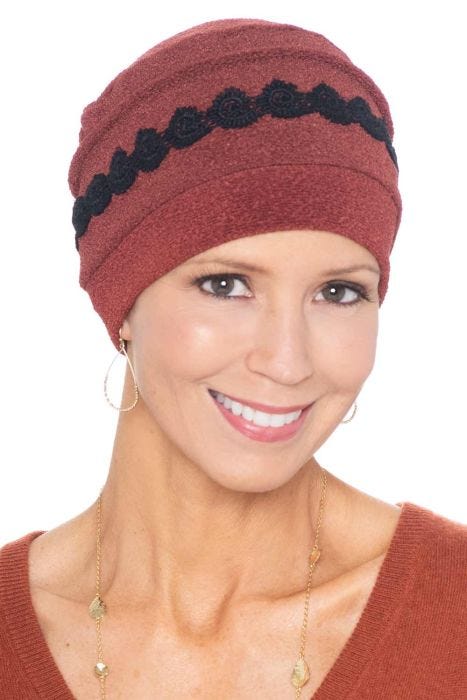 Woman in rust cancer hat with embroidered black detail around the cap