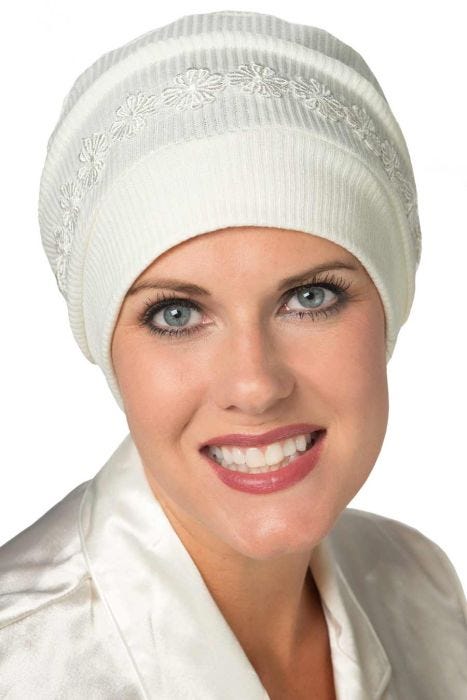 Woman in cream ribbed sleep cap or hat with embroidered band for chemo patients