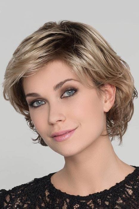 Woman in a chin length layered light blonde bob wig with side bangs