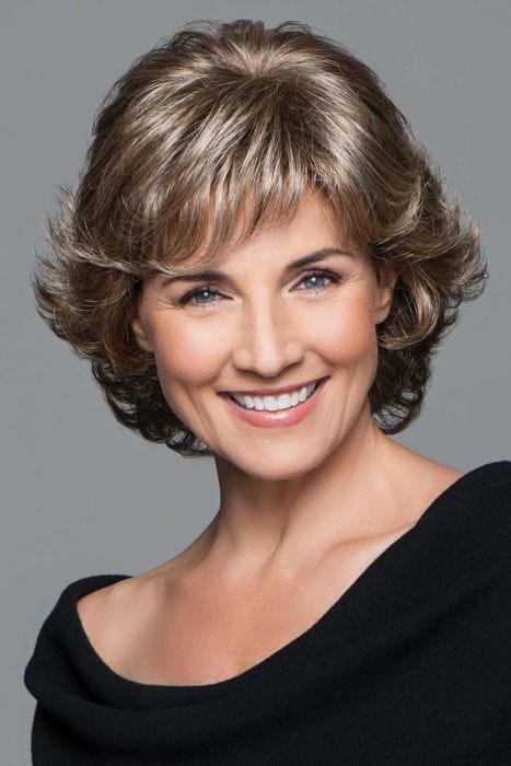 Woman in a short dark blonde curly wig with textured bangs
