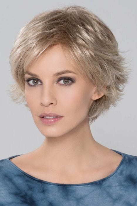 Woman in a light blonde pixie wig with longer hair on top and side bangs