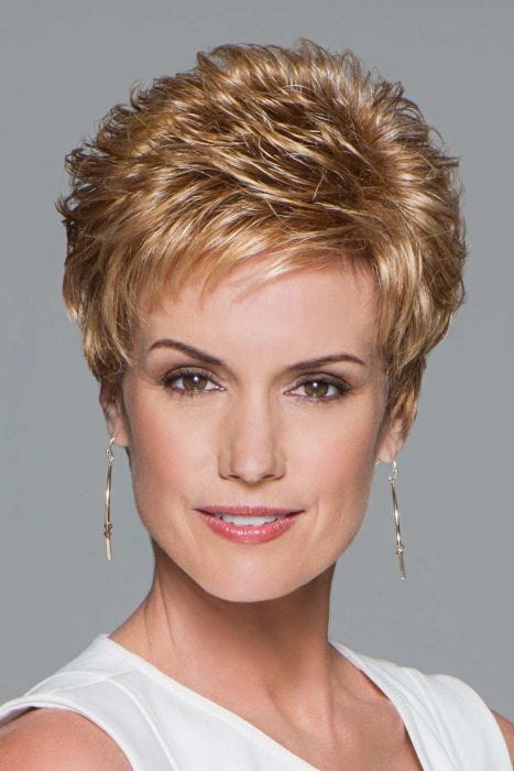 Woman in a petite strawberry blonde pixie wig with curled spiky layering on top and fringe bangs