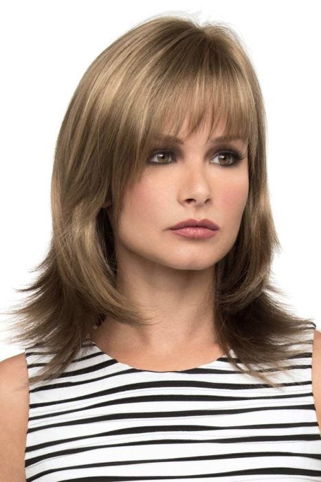 Woman in a shoulder length dark ash blonde wig with feathered layers and arched bangs