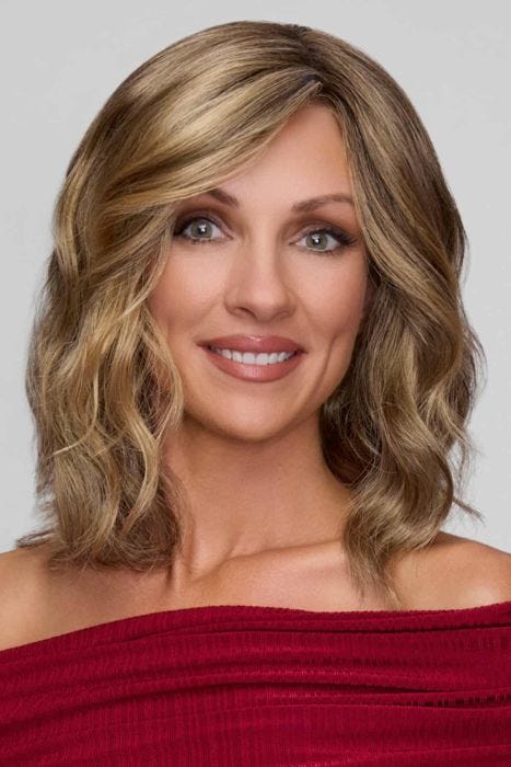 Woman in a past the shoulders light ash blonde wig with defined curls and dark roots