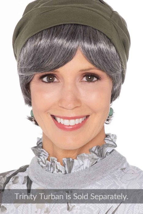 Woman in a short straight grey halo hair piece under an olive beanie hat