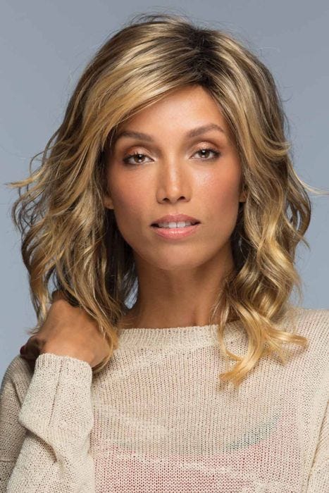 Woman in a past the shoulders curly light brown wig with side bangs