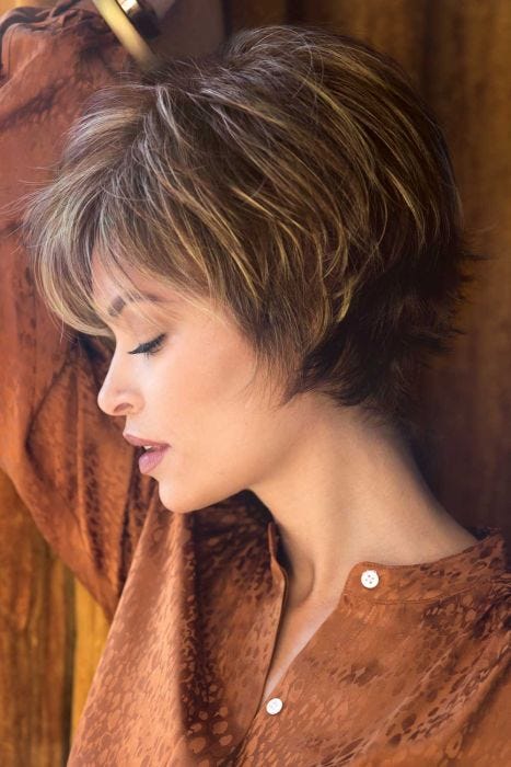 Woman in a long light brown pixie wig with fringe bangs and shorter, spiky layering in back
