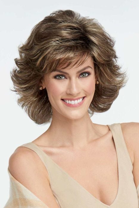 Woman in a medium brown, shoulder length blown out wig with dramatic layers and fringe bangs