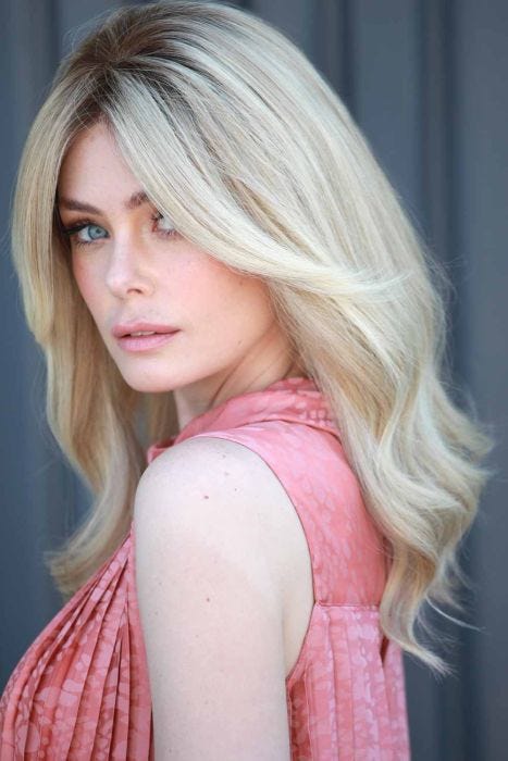 Woman in an extra long light blonde curly wig with long curtain bangs