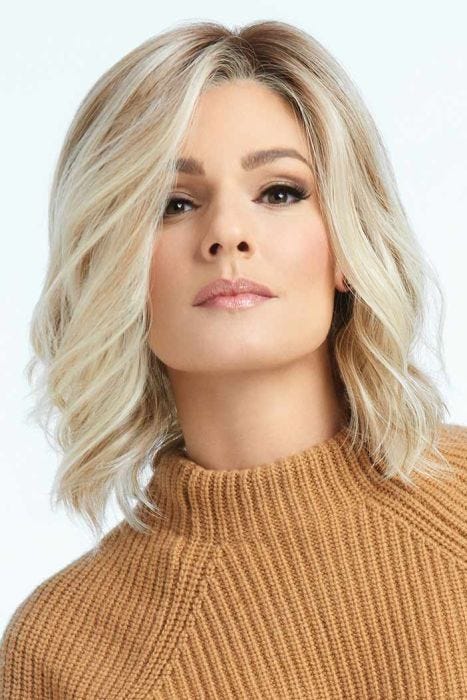 Woman in a shoulder length light blonde curly lace front wig with dark roots