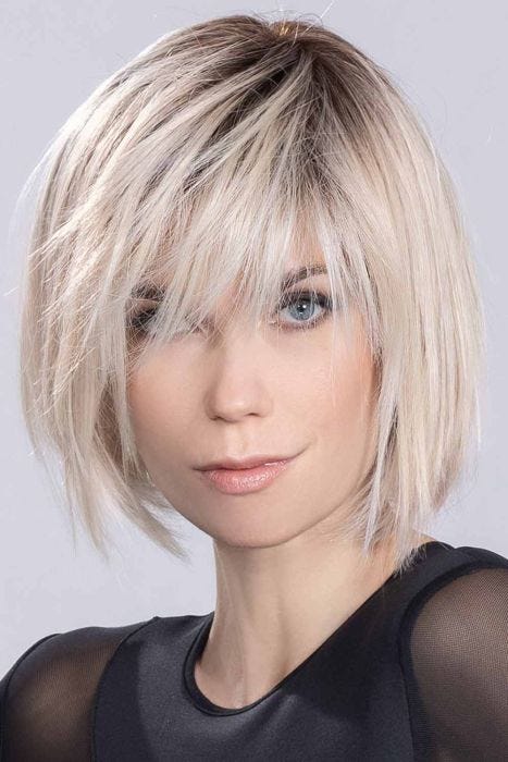 Woman in a past the chin choppy platinum lace front wig with long bangs