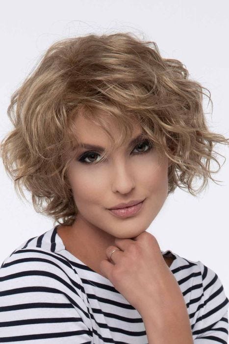 Woman in a chin length curly dark blonde layered bob wig
