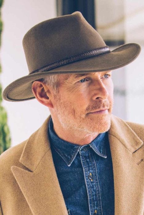 Older man in olive colored cool wool felt outback hat or fedora style brimmed hat